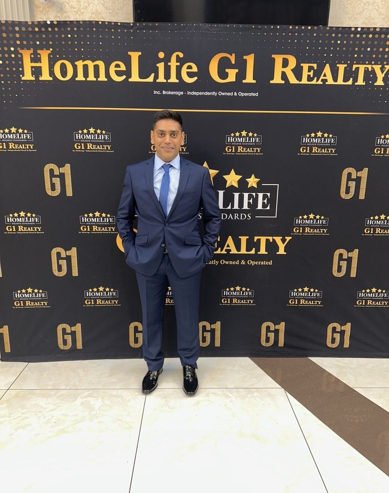 Robin Patel standing in front of a HomeLife G1 Realty awards backdrop.